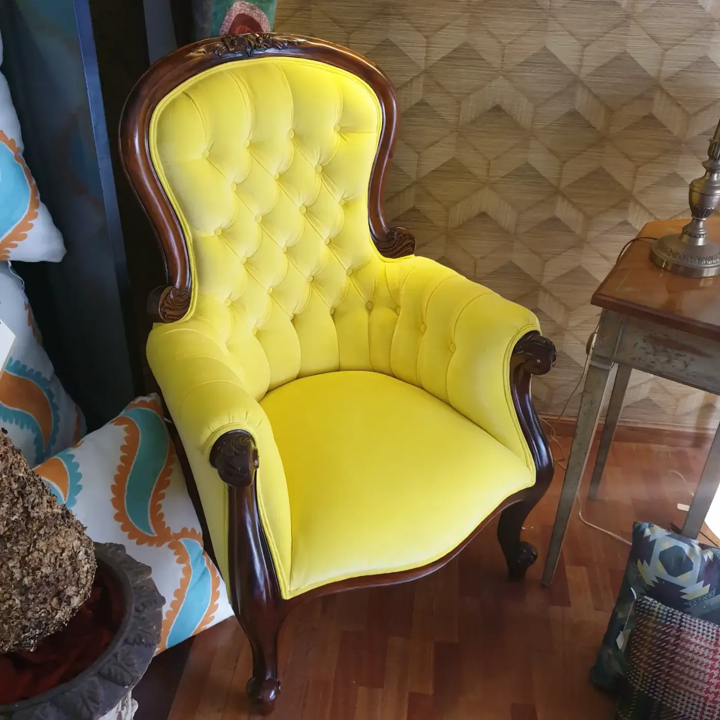 Butaca victoriana tapizada en terciopelo amarillo con capitoné y madera tallada