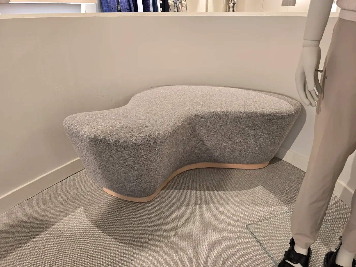 Banco curvo de diseño tapizado en tela gris con base de madera
