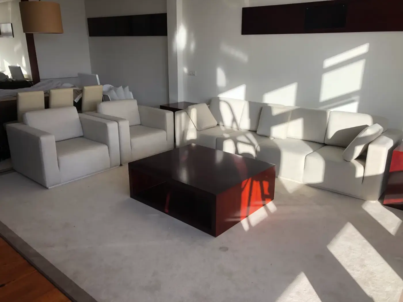 Conjunto de sofás y butacas tapizados en tela crema en salón moderno
