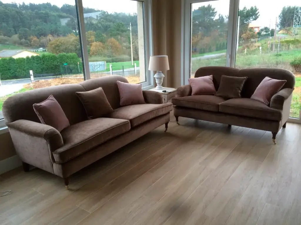 Conjunto de dos sofás marrones clásicos con respaldos curvos y patas de madera - salón con vistas